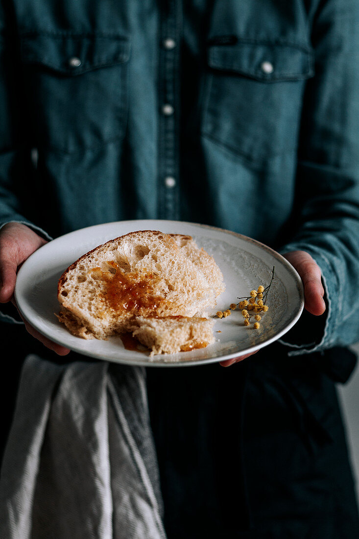 Woman showing slices of tasty fresh Brioche bread with brown jam on plate