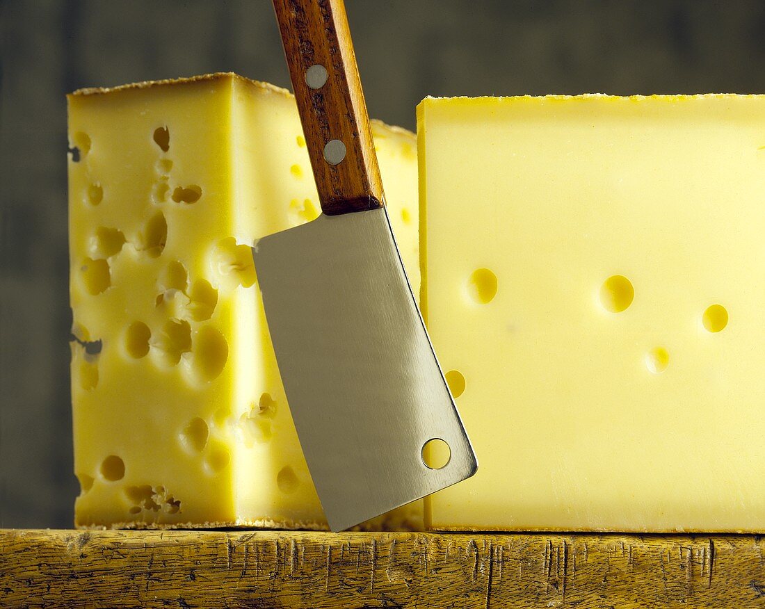 Two pieces of Emmental on wooden board with cheese knife