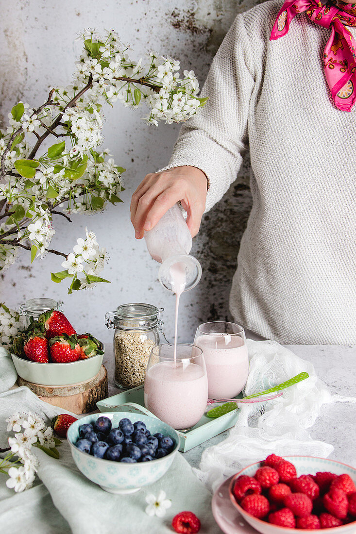 Puring homemade smoothie into glass for healthy breakfast with fresh berries