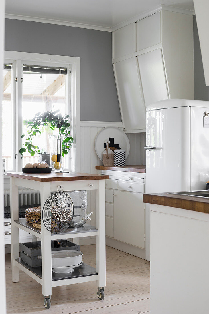 Serving trolley used as island counter in white country-house kitchen