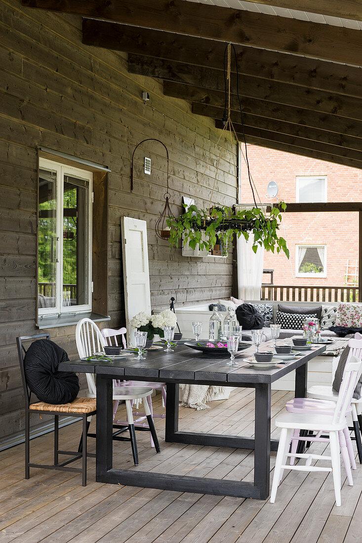 Set dining table on roofed terrace of wooden house