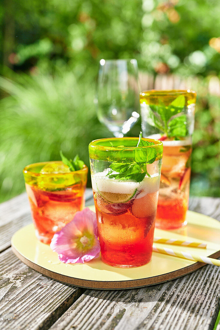 Iced tea with fruit and basil on a table in a summer garden