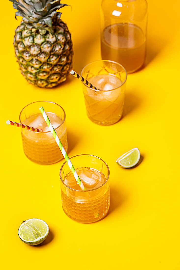 Eistee mit Ananas und Kokossirup in Gläsern auf gelbem Untergrund