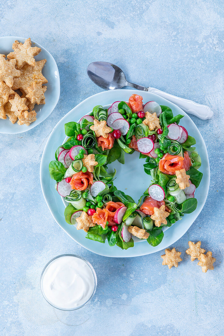 Salad in form of wreath with salmon, cucumber, radish, peas, corn and cheese cookies stars