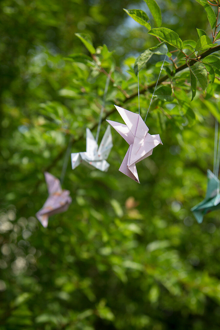 Papiervögel in Origami-Technik als Frühlingsdeko im Baum