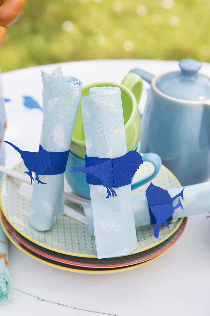 Handmade napkin rings with blue bird motifs on table set for summer meal in garden
