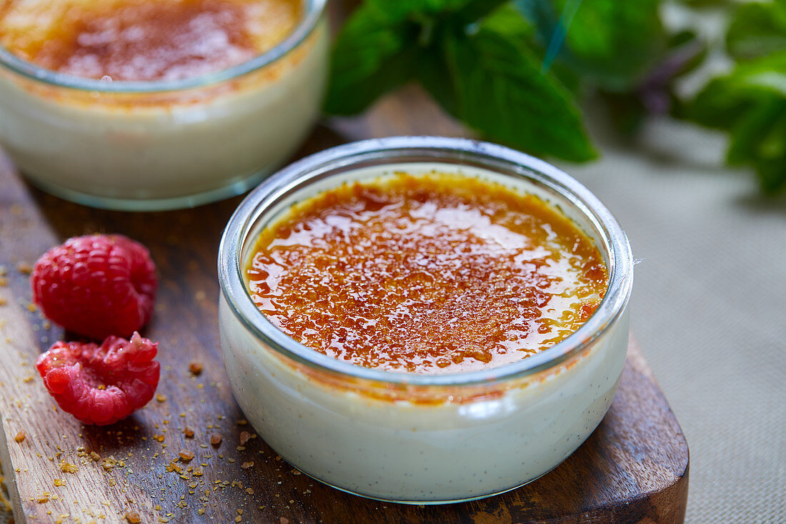 Crème brûlée und Himbeeren auf Schneidebrett