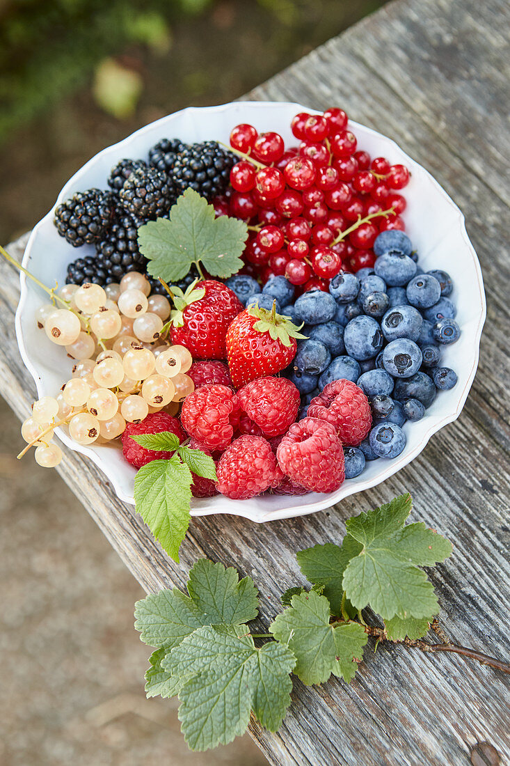 A plate of different berries on an outdoor table
