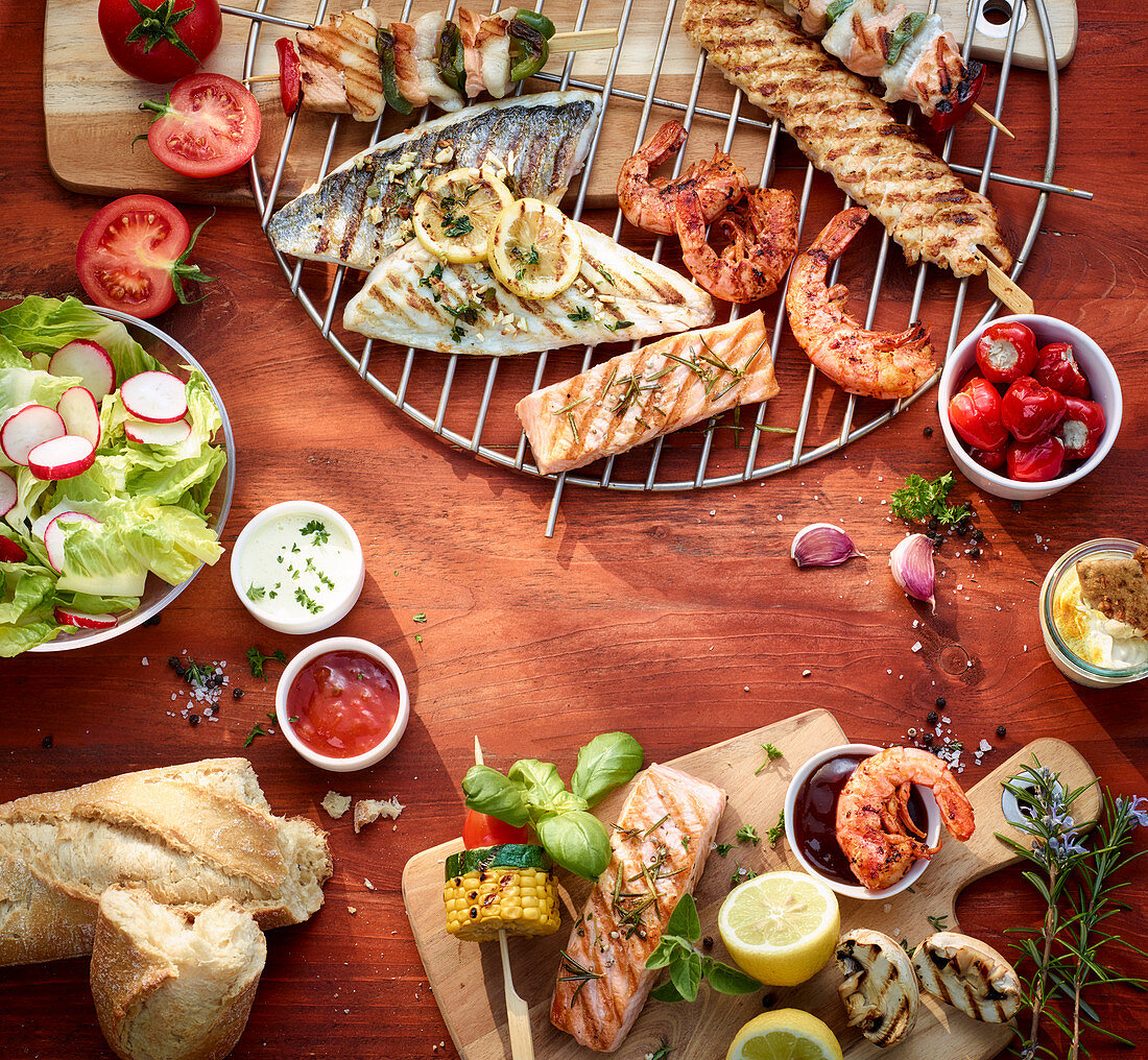Grilled fish, shrimp and kebabs with dips, lettuce and baguettes