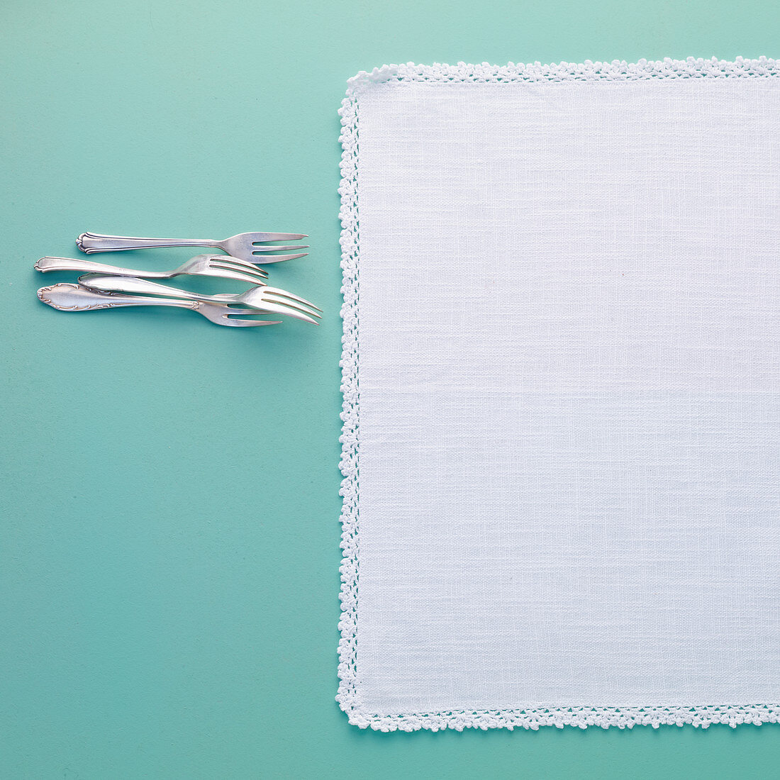 Linen tablecloth with a lace border and cake forks