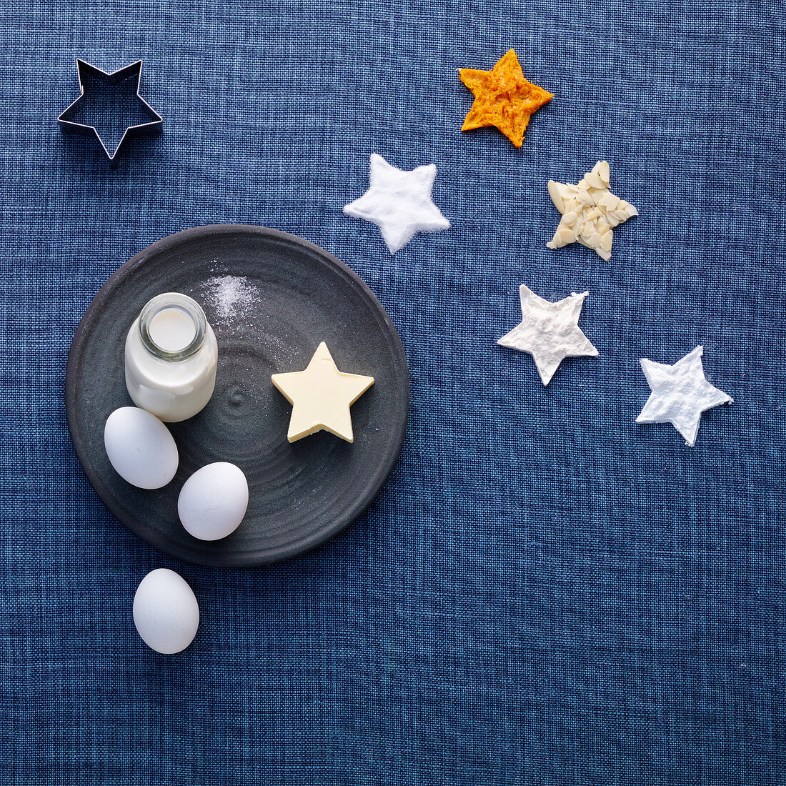 Ingredients and cookie cutters for orange and almond stars