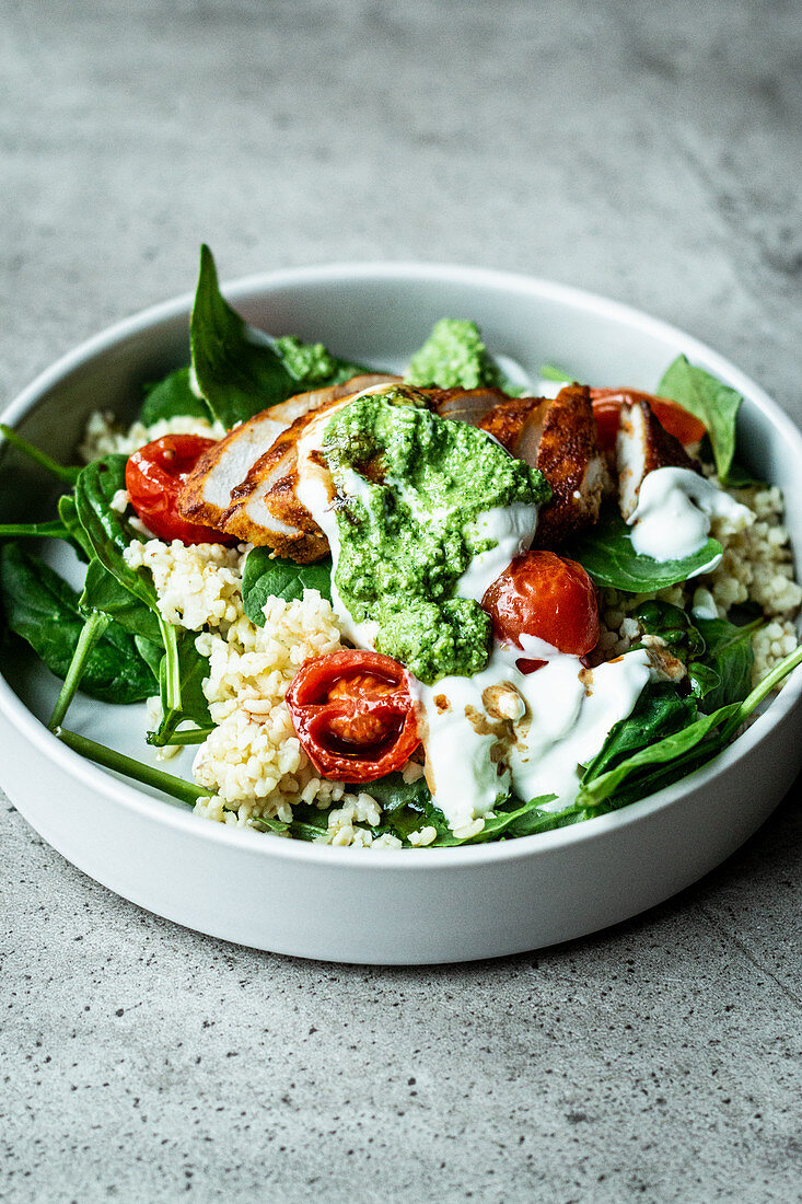 Fitness bowl with chicken breast, bulgur, spinach and pesto