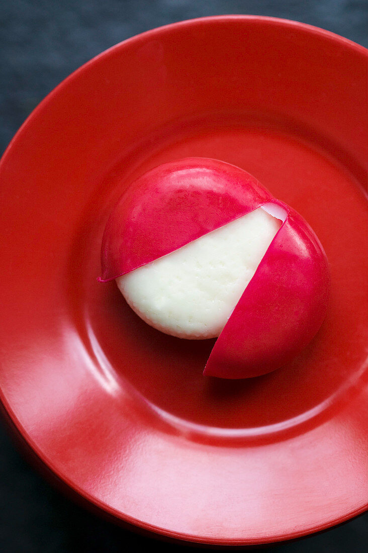 Babybel, aufgeschnitten, auf rotem Teller