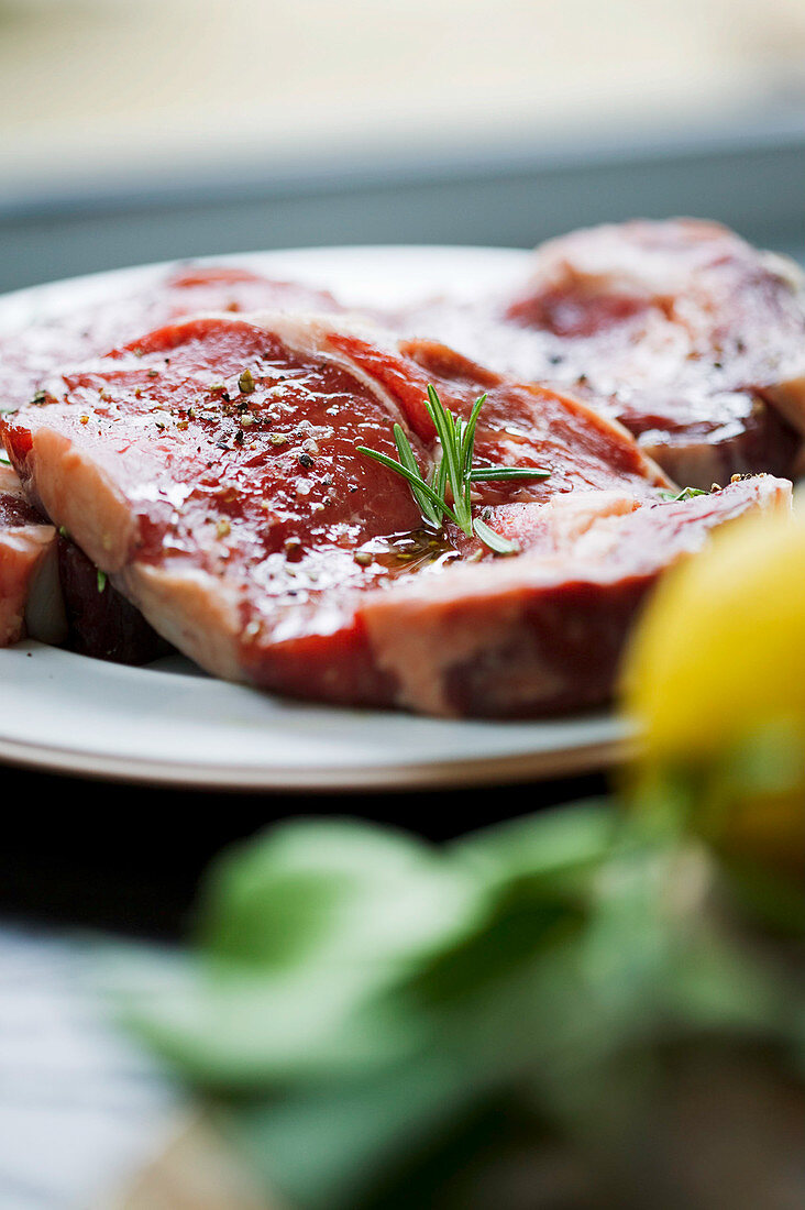 Rohe Rindersteaks mit Rosmarin auf Teller