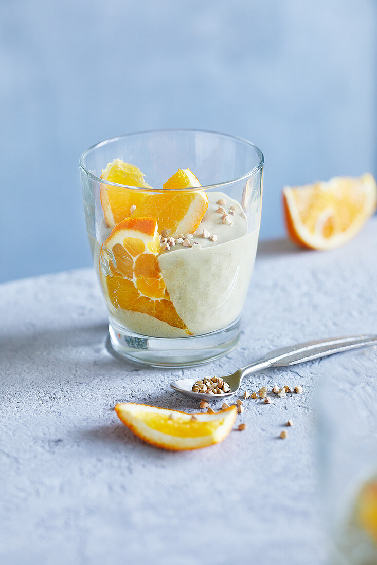 Avocado mousse with orange slices and buckwheat seedlings in a glass