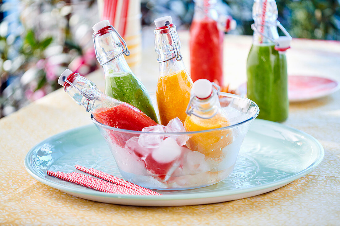 Red, yellow and green gazpacho in flip-top bottles