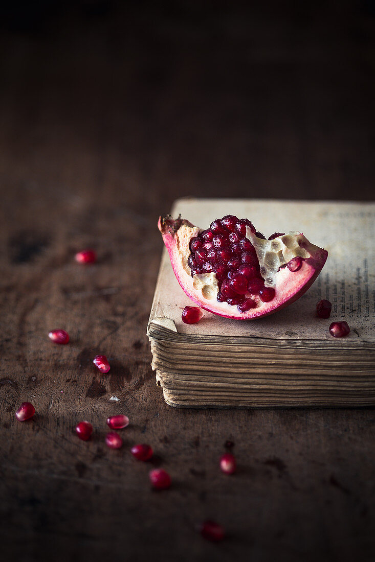Piece of a fresh pomegranate on a wooden surface