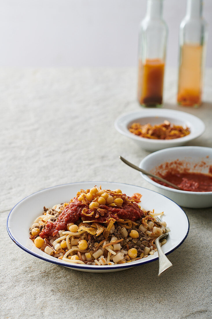 Koshari Traditional Egyptian dish - vegan mixed rice, pasta, lentils, with caramelized onions and tomato chili sauce