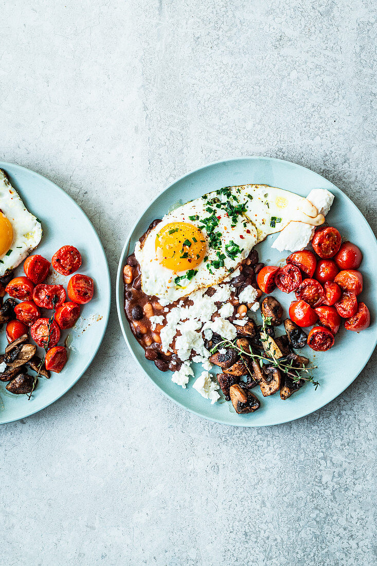 Vegetarisches englisches Frühstück mit Spiegelei, Pilzen, Tomaten und Feta