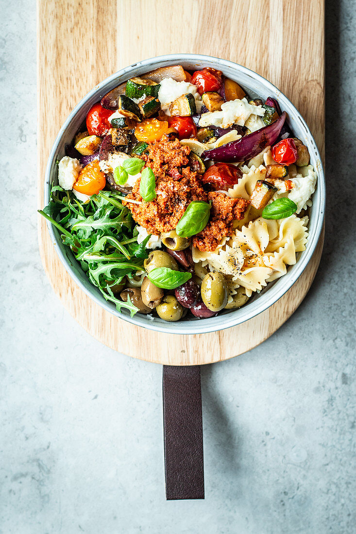 Nudel-Bowl auf italienische Art mit Tomaten, Rucola, Oliven und Pesto