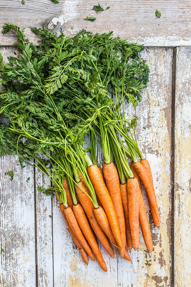 A bunch of fresh carrots on a wooden background.