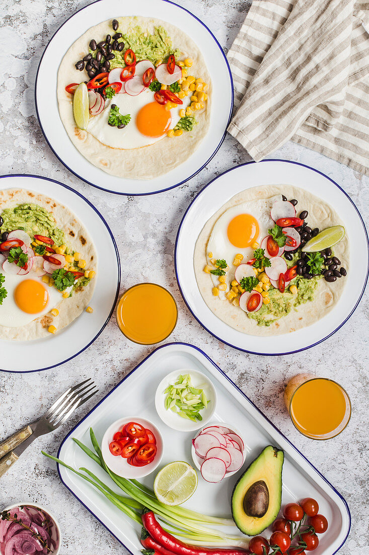 Wraps mit Spiegelei, Guacamole, Chilis, schwarzen Bohnen, Mais und Radieschen