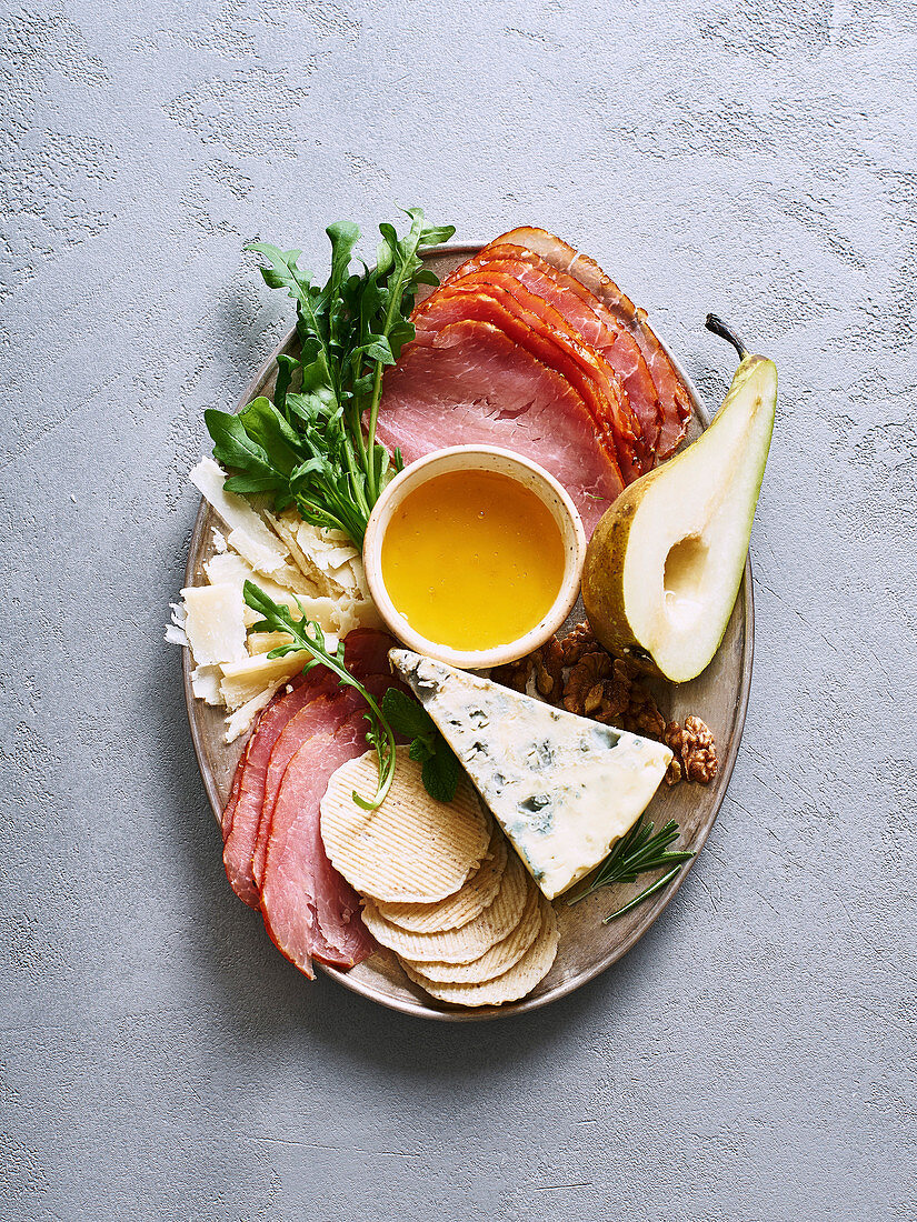 Vorspeisenplatte mit Käse, Schinken, Birne, Nüssen, Rucola und Honig