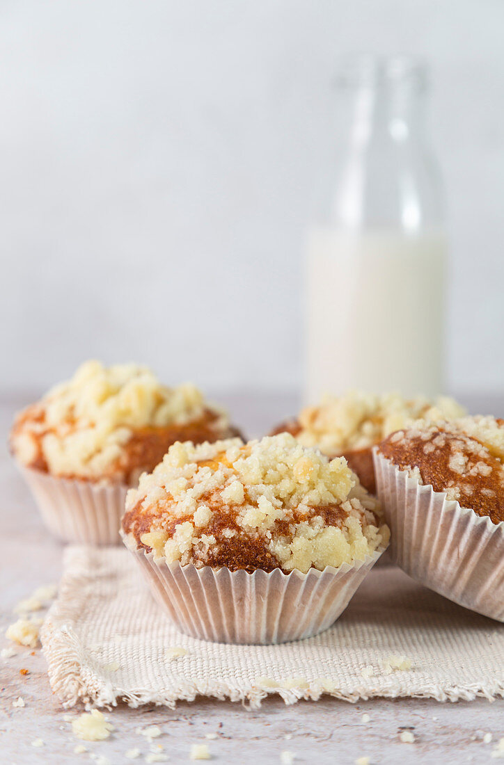 Soft yoghurt muffins, topped with vanilla crumble, served on napkin, with bottle filled with milk.