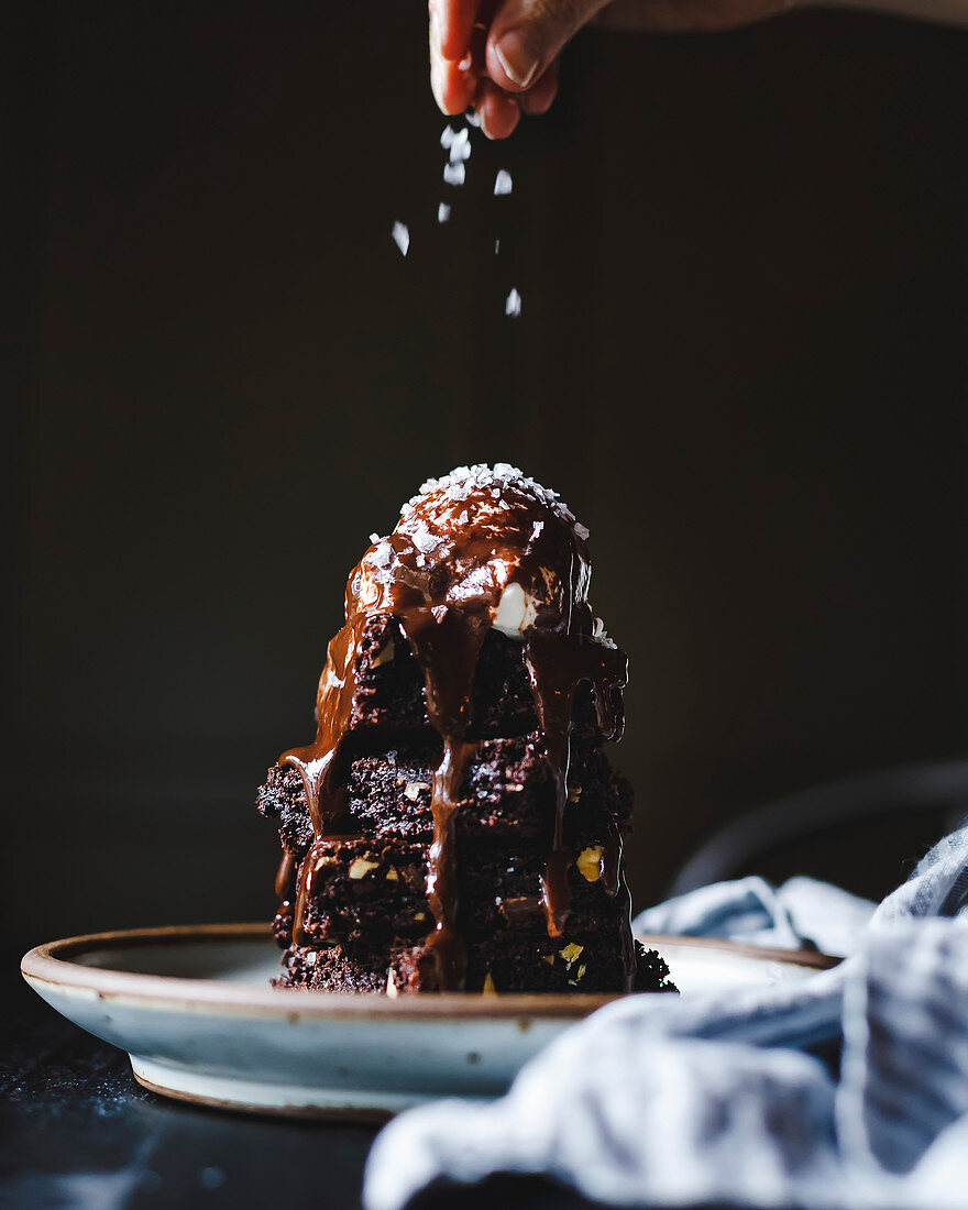 A stack of chocolate brownies, covered in ice cream and chocolate sauce