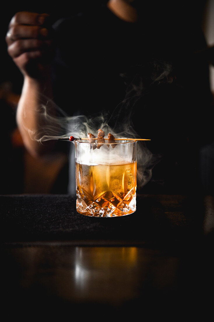 Dampfender Cocktail mit Spießchen auf Bartheke