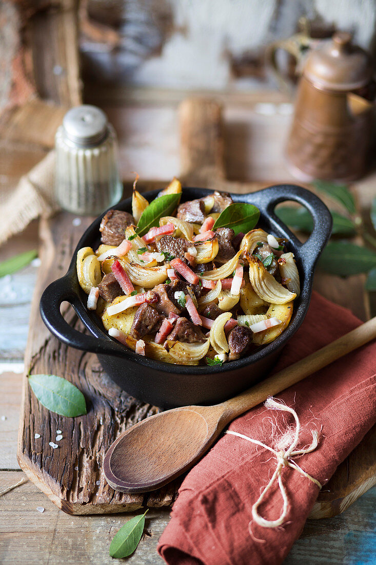 Roast meat with potatoes and onions on wooden table