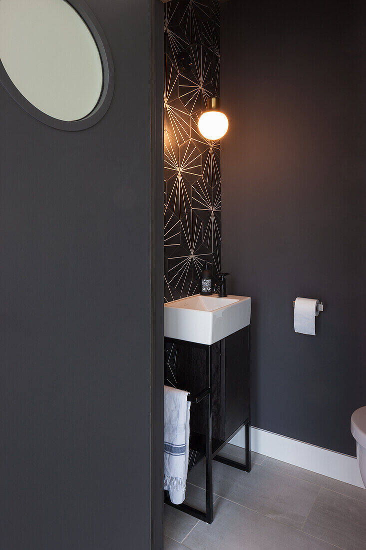 Dunkel gestaltetes Gäste-WC mit geometrischem Wandmuster