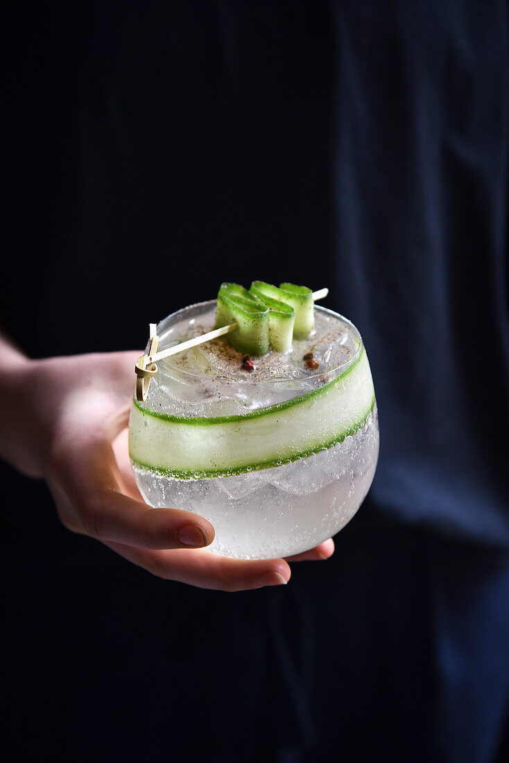 Cocktail with Cucumber in a womans hands