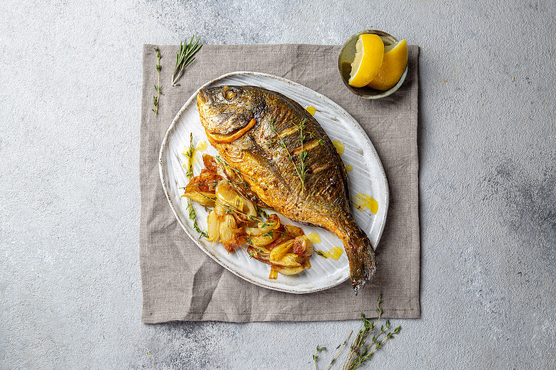 Grilled sea bream or dorada on gray plate. Gray background.