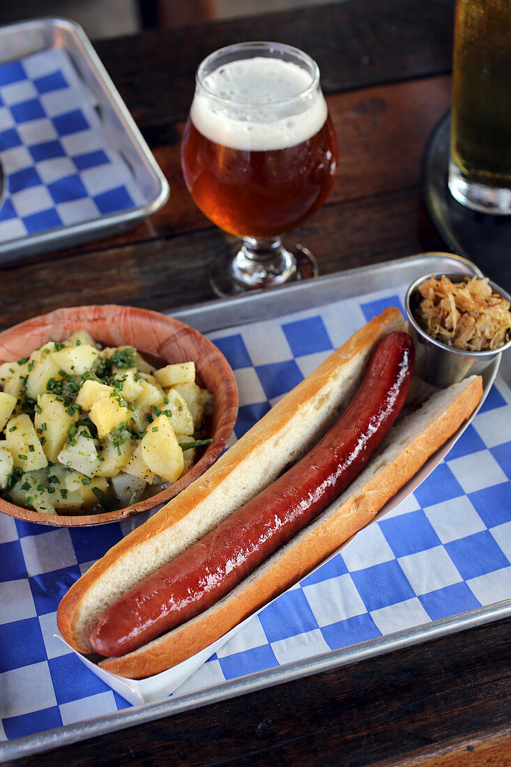 Hot Dog mit Kartoffelsalat und Sauerkraut im Biergarten
