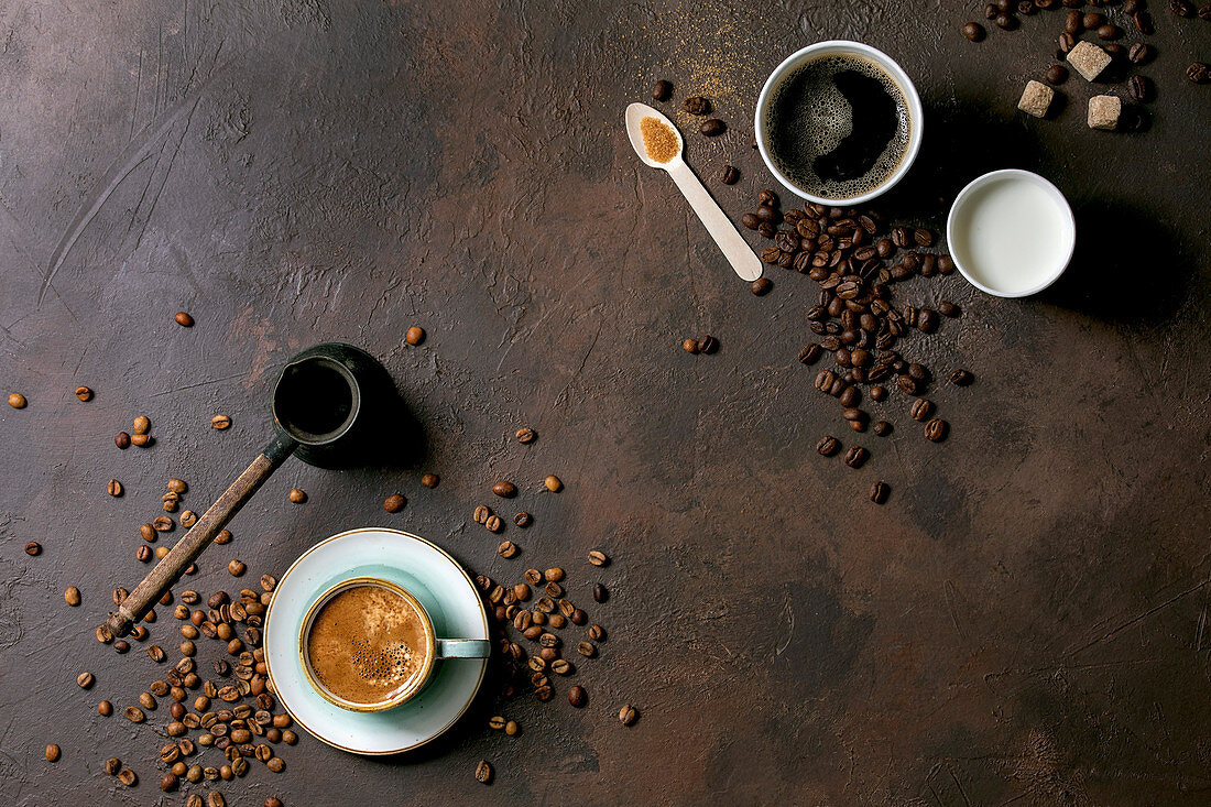 Kaffee in Keramiktasse und Cezve daneben Kaffee und Milch in Pappbechern
