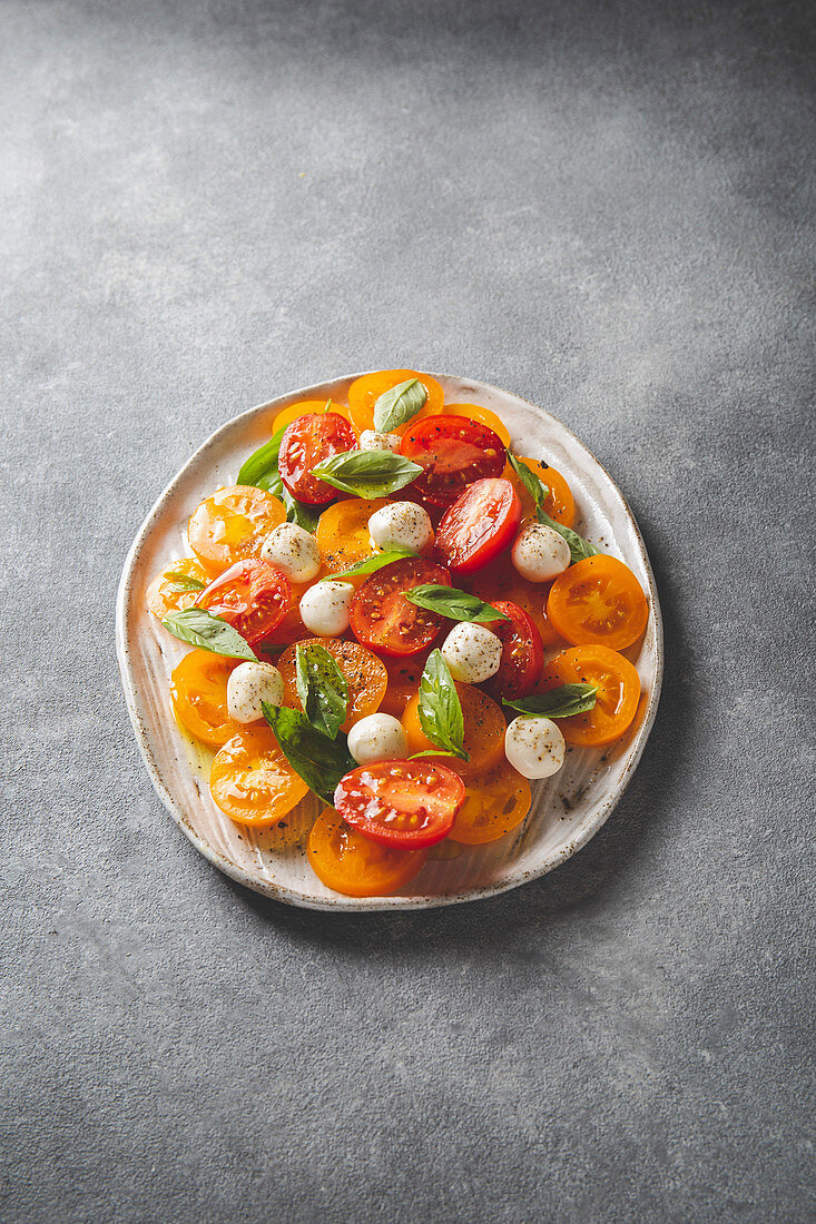 Italian caprese salad with red and yellow tomatoes, mozzarella and basil