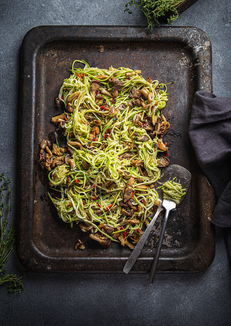 Vegetarian zucchini pasta with mushrooms on baking tray