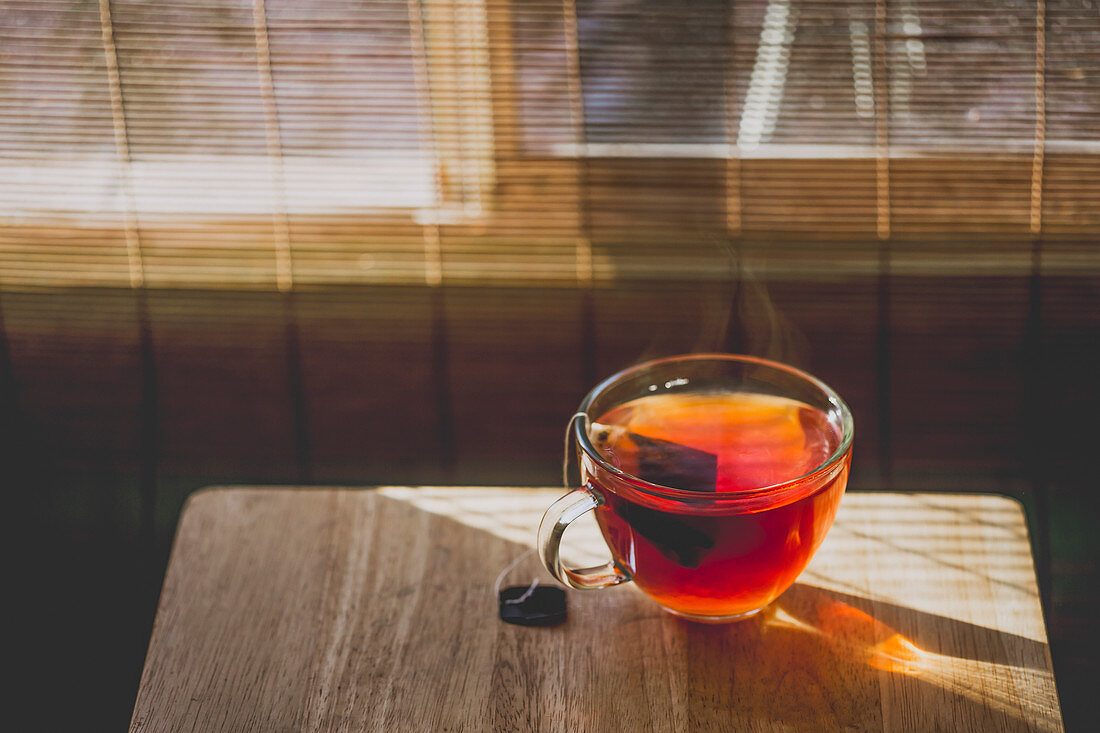 Eine Glastasse Tee auf Tisch im Sonnenlicht