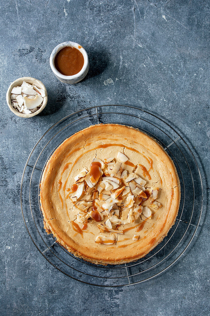 Käsekuchen mit Karamellsauce und Kokoschips auf Abkühlgitter