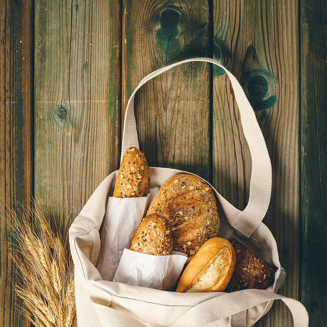 Eco bag with fresh bread on wooden background