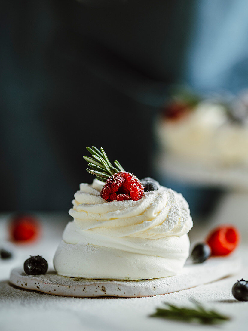 Mini Pavlova cake with fresh berries and fresh green rosemary