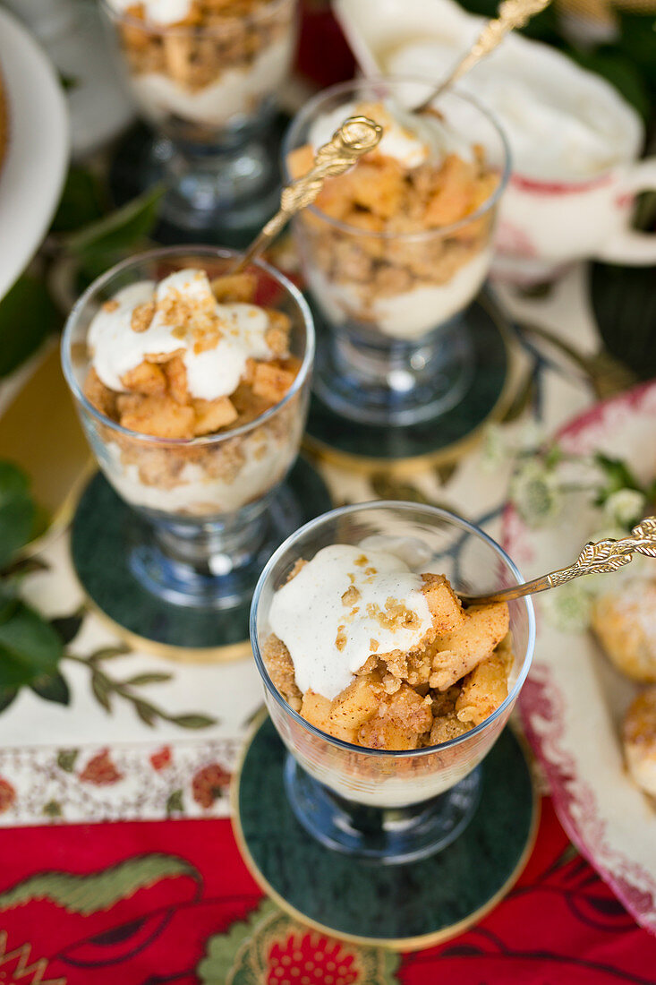 From above cups of yummy dessert with pieces of apple placed on plate against cloth