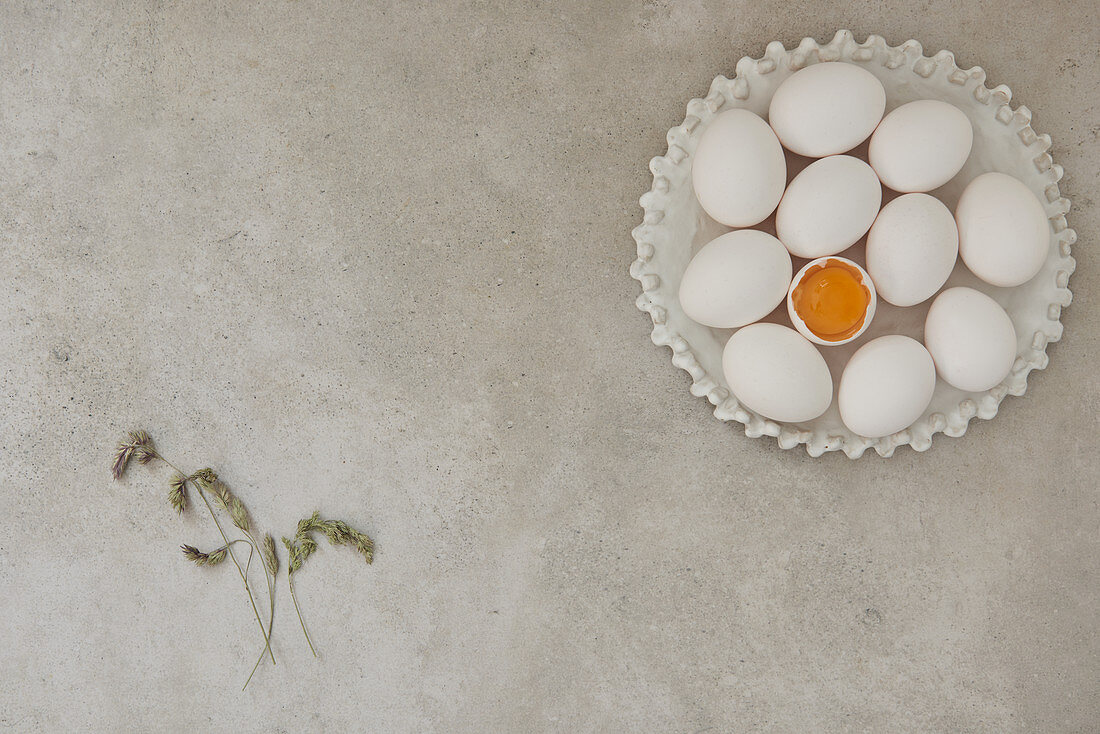 Weisse Eier auf Keramikteller mit Gräserblüten