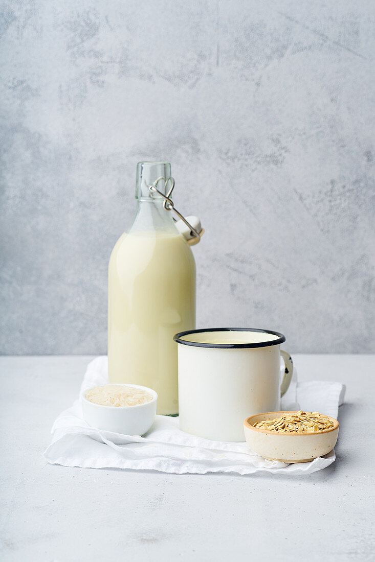 Reismilch und Hafermilch in Bügelflasche und Emaillebecher