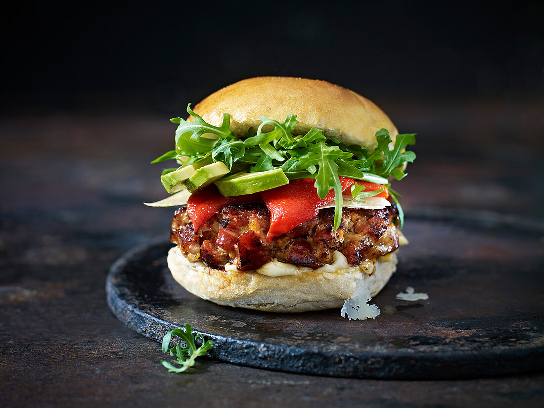 A Spanish burger with salad on a dark background