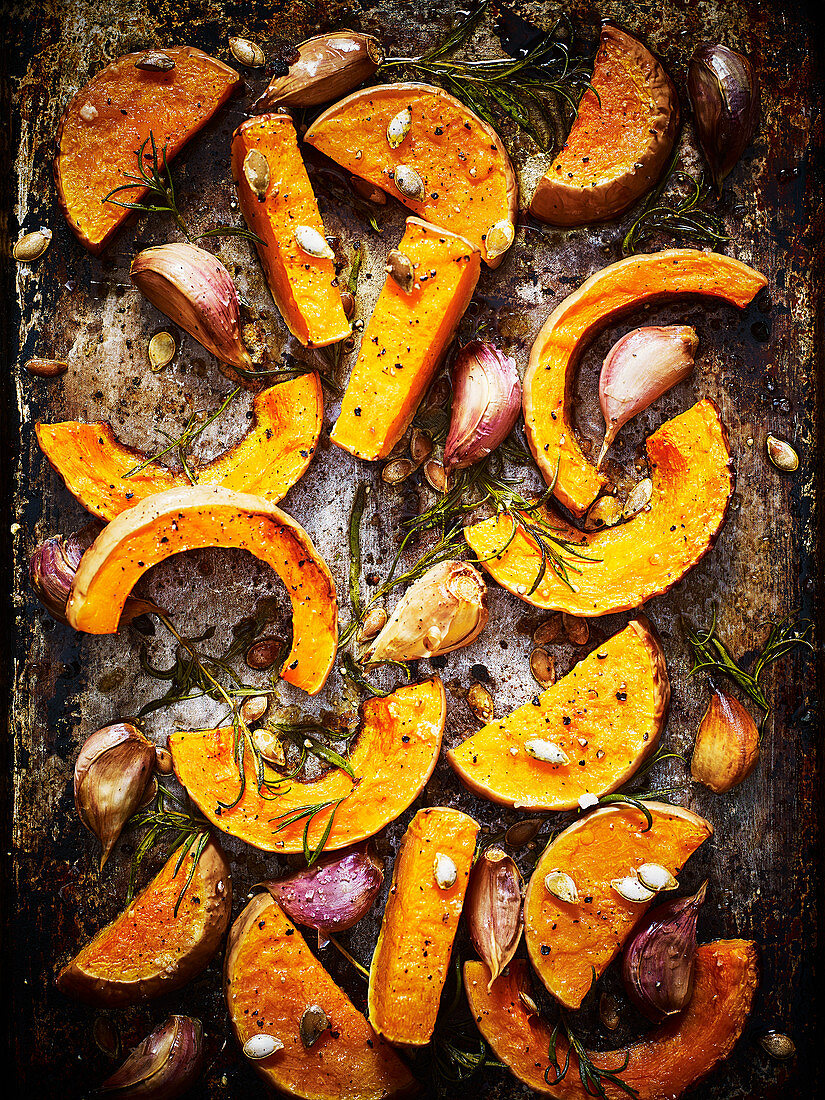 Roasted sliced pumpkins with garlic cloves and herbs