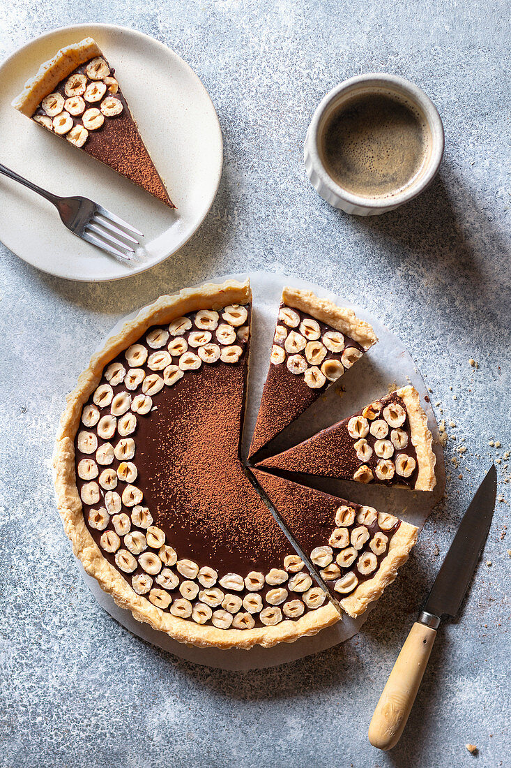 Chocolate hazelnut tart and a cup of coffee on the table.