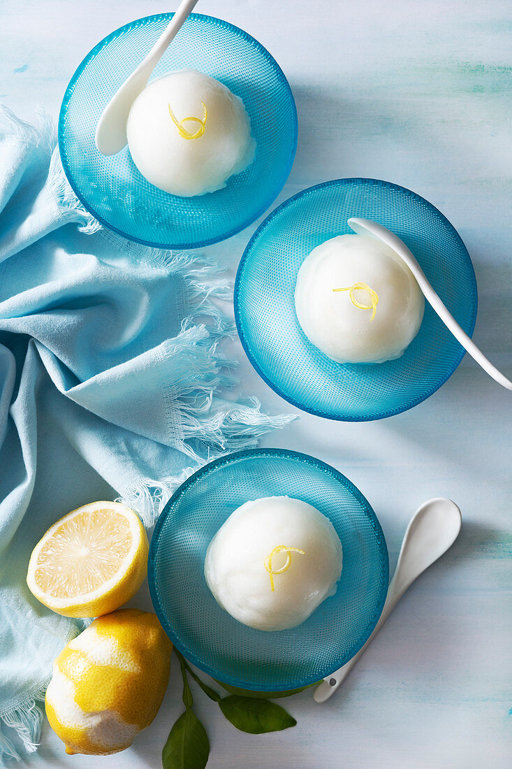 Zitronensorbet als Kugeln in blauen Dessertschälchen