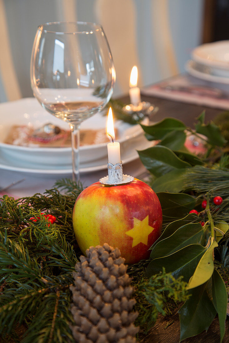 Apple with star motif used as candle holder on set table